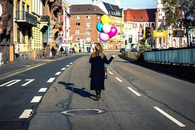 Rear view of women walking on road along buildings