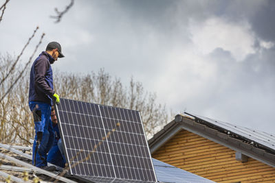 Man working on roof against sky