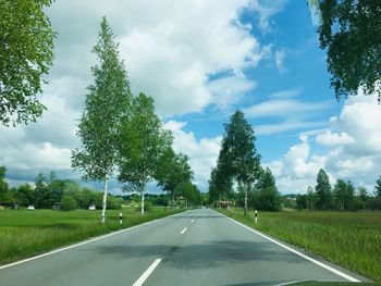 Empty road amidst trees against sky