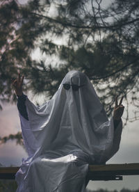 Low angle view of person wearing mask hanging on tree