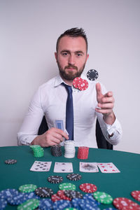 Portrait of man throwing gambling chips while playing poker at table