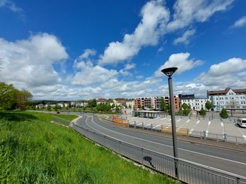 Road amidst field against sky in city