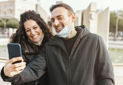 Portrait of smiling young man using mobile phone in city