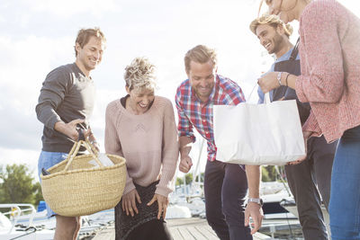 Happy friends preparing for picnic on pier at harbor