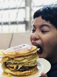 Boy with mouth open holding pancakes in plate