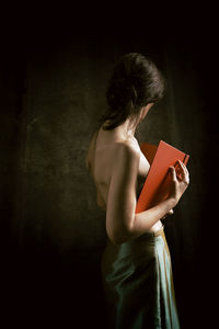 Woman in green skirt reading a book in romantic attitude
