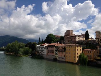 Buildings by river against sky