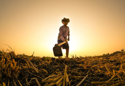 Man working on field against clear sky during sunset