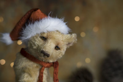 Christmas card greeting with cute handmade teddy bear with red santa cap on brown background