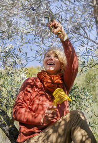 Smiling woman picking olives in olive grove