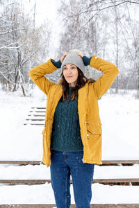 Full length of a smiling woman standing in snow