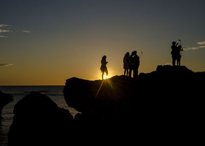 Silhouette of people standing at sunset