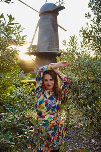 Portrait of smiling young woman standing against plants