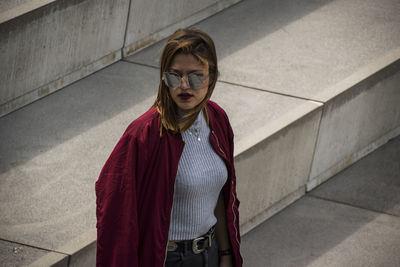 High angle view of young woman in sunglasses standing on steps