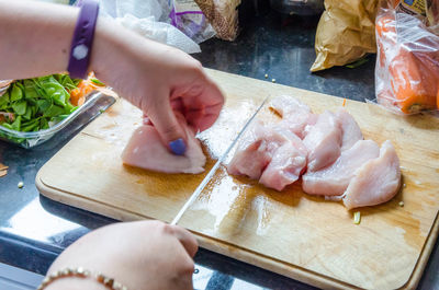 Close-up of woman chopping meat on cutting board