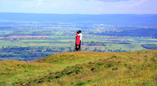 Rear view of man standing on landscape against sky