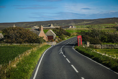 Road amidst field against sky