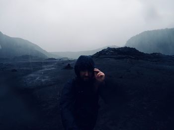 Mid adult man standing on mountain during rainy season