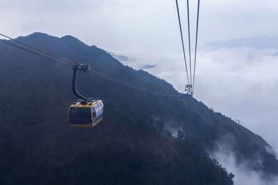 Overhead cable car in mountains against sky