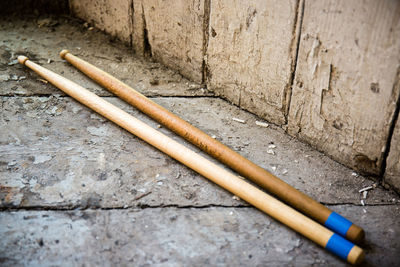 Close-up of abandoned drumsticks on floor by wall