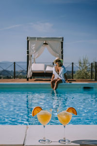 Young woman in swimming pool against sky