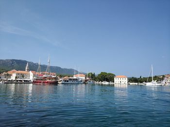 Sailboats in sea by buildings against sky