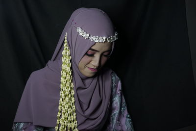 Portrait of young woman against black background