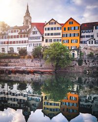 Buildings by river in town against sky