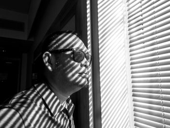 Young man wearing sunglasses by blinds
