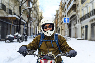 Close-up of a man sitting with his vintage motorcycle on the street.