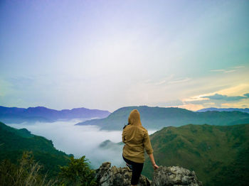 Rear view of woman standing on mountain against sky