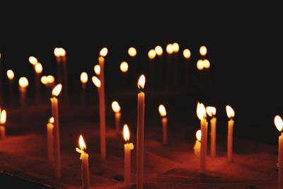 Lit candles in illuminated temple against building at night