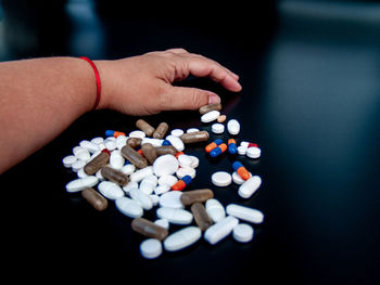 Cropped hand holding medicines over black background