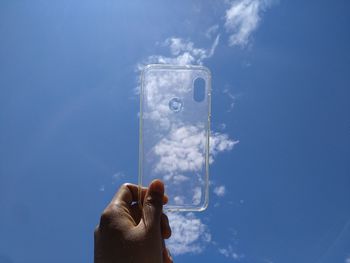 Person holding phone case against blue sky