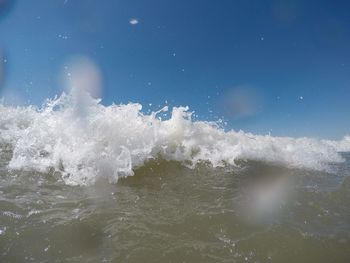 Water splashing in sea against sky