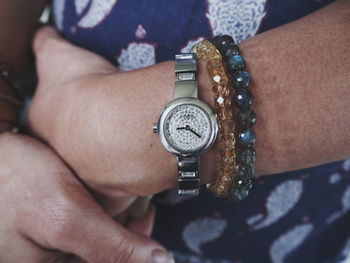Midsection of woman wearing bead bracelets and wristwatch