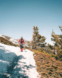 Man walking on snow covered mountain against clear sky