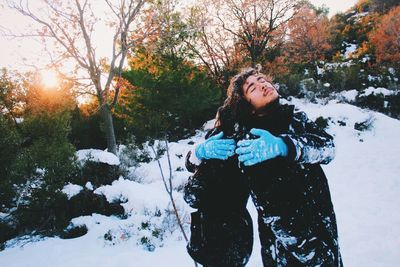 Portrait of young man standing against trees in winter