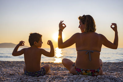 Friends on beach against sky during sunset