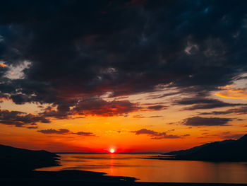 Scenic view of sea against dramatic sky during sunset