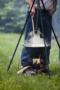 Low section of man preparing food over bonfire