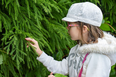 Portrait of young woman standing by plants