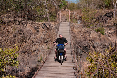 Man riding motorcycle on footbridge