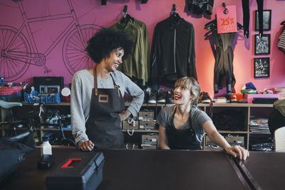 Happy female mechanics looking at each other at table