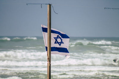 Information sign hanging on pole against sea