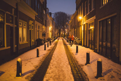 People walking on snow covered city at night
