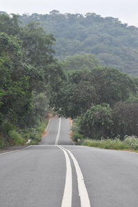 Empty road amidst trees and mountains