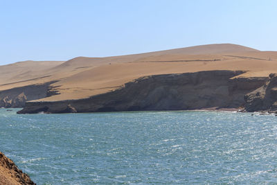 Scenic view of sea and mountains against clear blue sky