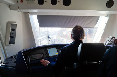 Rear view of man sitting in cockpit of train