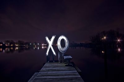 Pier over lake against sky at night